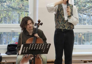 Muzyk gra na wiolonczeli, a drugi śpiewa.