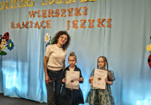 Nauczycielka i dwie dziewczynki biorące udział w konkursie recytatorskim